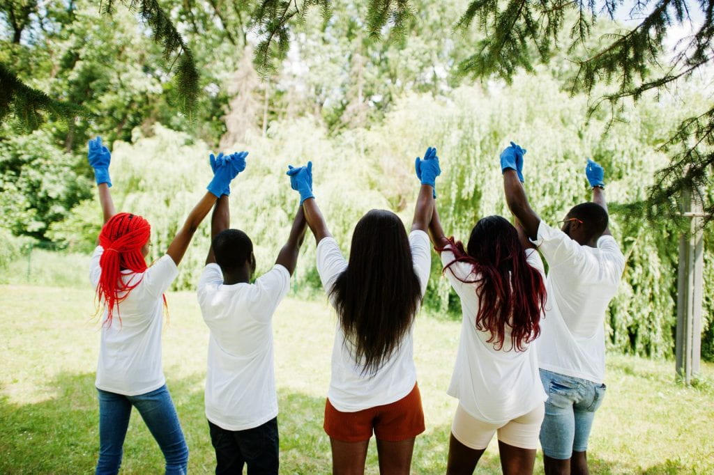 Back of group of African volunteers holding their hands up.
